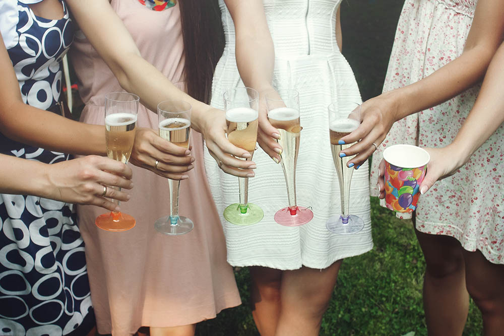 hands of woman holding colorful glasses and toasting