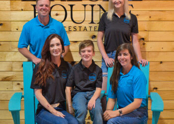 Group of people in blue shirts sitting on blue deck chairs in front of wood paneling