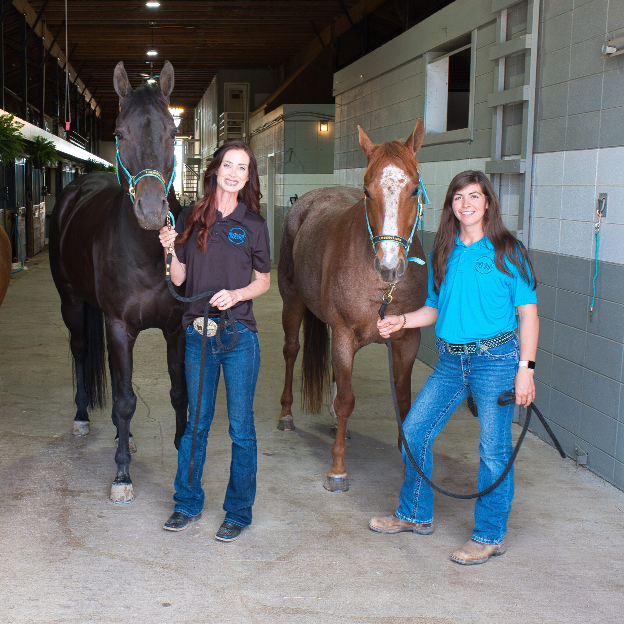 Two women with horses in a stable