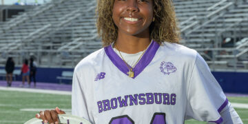 Female lacrosse goaltender standing on a lacrosse field