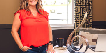 Woman standing next to desk with a swirlie statue on the desk
