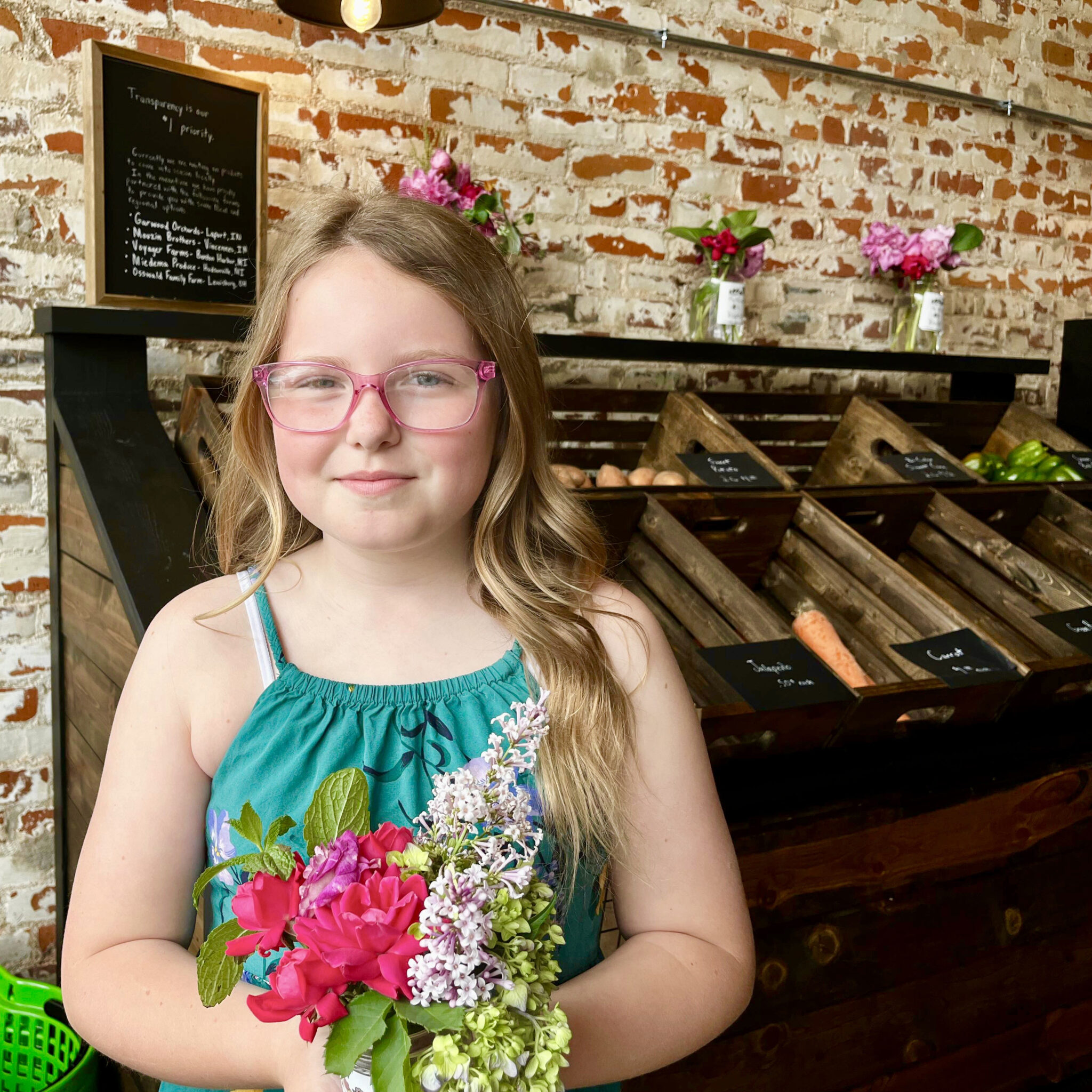 11 year old girl holding flowers in front of a brick wall