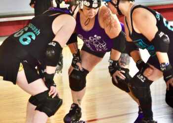 Three roller derby skaters lined up on the track