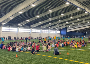 Elementary school students sitting on a football field