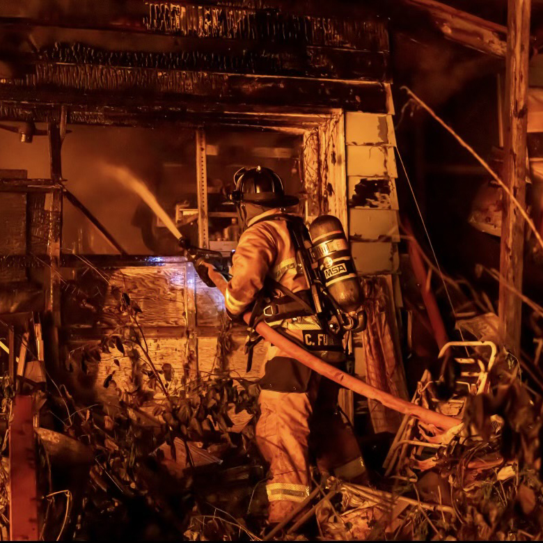 Firefighter holding a hose and putting out flames