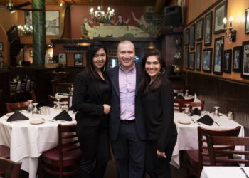 2 women and a man standing in a restaurant