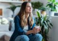 Shot of young woman drinking a cup of coffee while sitting on couch in living room at home.