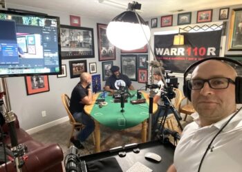 Professional podcast recording session for "Those AshHoles" featuring hosts at a green round table with a "WARRIOR" banner in the background.