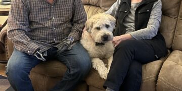 Rene’ and Julie sitting on the couch with their dog