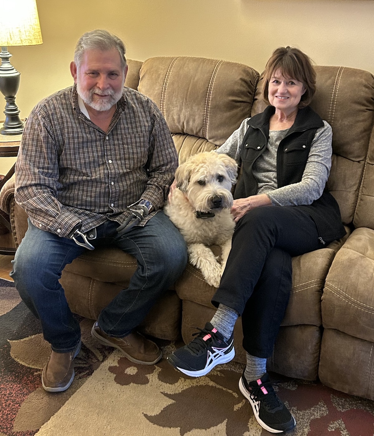 Rene’ and Julie sitting on the couch with their dog