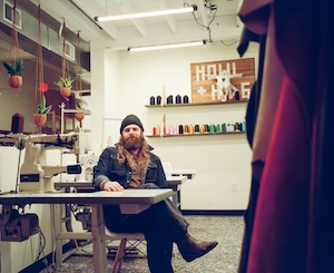 Founder Christian Resiak in the Howl + Hide workshop, surrounded by leatherworking tools and supplies