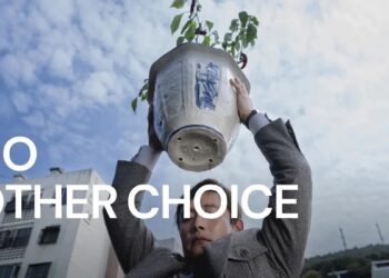 A man holding a plant above his head with the sky behind him.