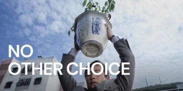 A man holding a plant above his head with the sky behind him.