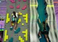 Two children using safety harnesses to scale creative themed rock climbing walls at an indoor adventure park.