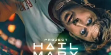The poster features a close-up, upside-down shot of Gosling as the protagonist, Dr. Ryland Grace, a schoolteacher-turned-astronaut. He appears disoriented, with wide blue eyes and light brown hair, wearing a white t-shirt with dark trim and a pair of aviator sunglasses tucked into the collar. The background shows blurred, glowing lights and high-tech equipment, suggesting he is inside the Hail Mary spacecraft. The film's title, "PROJECT HAIL MARY," is prominently displayed in a stylized white font.