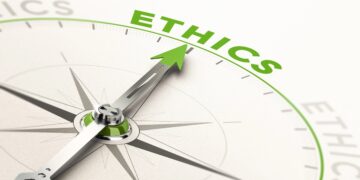 A close-up of a silver compass with a bright green needle pointing directly toward the word "ETHICS" written in bold, green capital letters. The compass face is white and minimalistic, with the word repeated faintly along the edge, symbolizing a moral compass or ethical guidance.