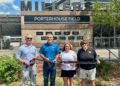 A bright outdoor shot of a ribbon-cutting ceremony at PorterHouse Contracting Field in Noblesville, Indiana. Standing in front of a tan stone and brick monument that reads "MILLERS - PORTERHOUSE FIELD," four individuals hold a long black ribbon. From left to right are Noblesville Schools Superintendent Dr. Dan Hile, James Porter, Kristi Porter (owners of PorterHouse Contracting), and Noblesville High School Athletic Director Leah Wooldridge. The monument features several black plaques recognizing various sponsors. In the background, the metal bleachers and fencing of the sports complex are visible under a clear, sunny sky.