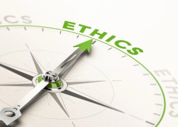 A conceptual close-up illustration of a metallic compass on a white surface. The green arrow of the compass needle points directly toward the word "ETHICS" printed in bold, bright green text along the upper curve of the dial. The word is repeated in fainter gray text along other parts of the ring.