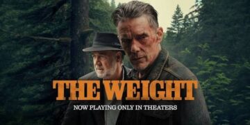 Poster for the movie "The Weight" showing Ethan Hawke and Russell Crowe. The foreground features a rugged, serious-looking Ethan Hawke with short, graying hair and dynamic facial features. Slightly behind him to the left stands Russell Crowe, wearing a dark fedora hat and a matching jacket over a button-up shirt, looking off to the side. They are positioned against a dense, dark green pine forest backdrop. The title "THE WEIGHT" is prominently displayed across the bottom in large, bold orange block letters, with the tagline "NOW PLAYING ONLY IN THEERS" written underneath in smaller white text.